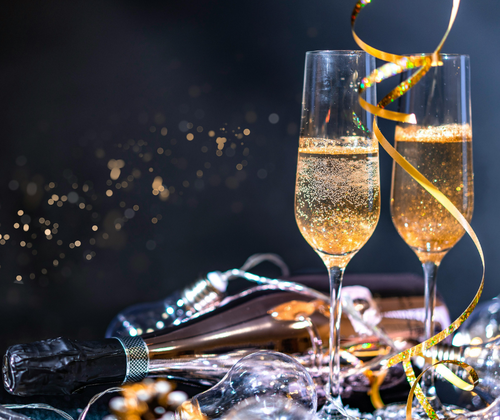 Zwei gefüllte Sektgläser, daneben liegt eine Flasche Sekt