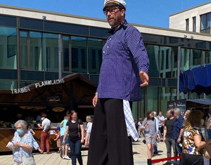 Ein Mann auf Stelzen, verkleidet als Matrose spaziert über den Fischmarkt.