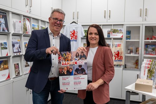 Mann und Frau halten ein Veranstaltungsplakat in den Händen