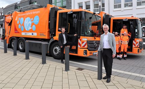 Mehrere Männer vor zwei Müllwagen