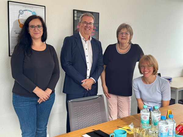 Drei Frauen und ein Mann hinter einem Tisch