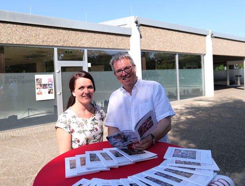 Mann und Frau hinter einem Tisch mit Prospekten 