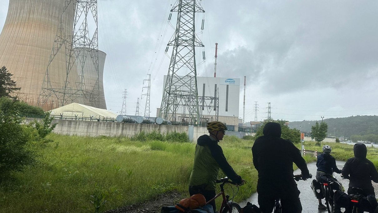 Radler fahren an einem Atomkraftwerk vorbei