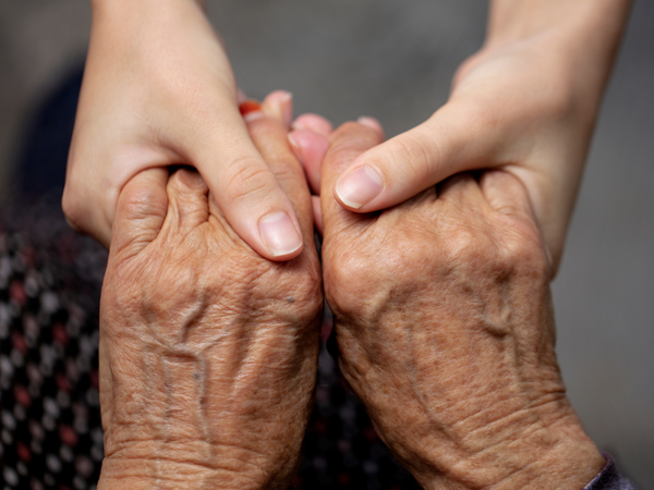 Zwei junge Hände halten zwei alte Hände