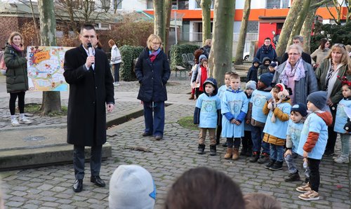 Bürgermeister mit Mikrofon spricht zu Kindern