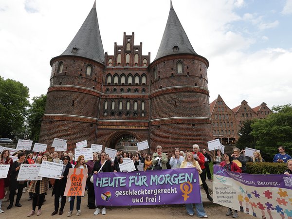 Personengruppe mit Bannern und Plakaten vor einem Stadttor