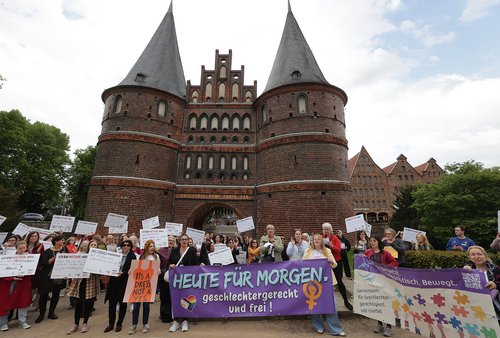Personengruppe mit Bannern und Plakaten vor einem Stadttor