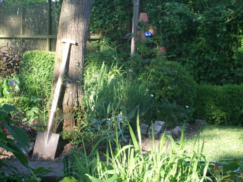Ein Spaten steht an einem Baum in einem Garten