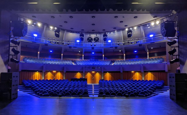 Innenansicht des Stadttheaters mit Blick von der Bühne in den Saal hinein, im blauen Scheinwerferlicht. 