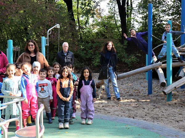 Kinder und Erwachsene vor einem Klettergerüst auf einem Spielplatz