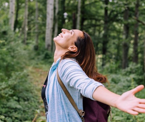 Frau mit offenen Armen in einem Wald