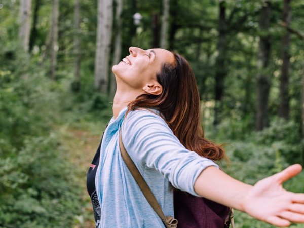 Frau mit offenen Armen in einem Wald