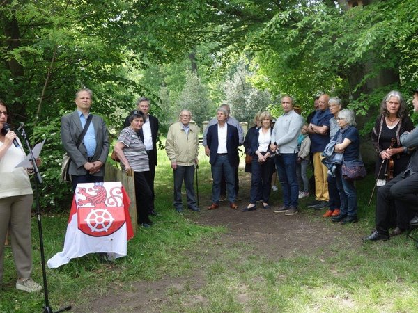 Mehrere Personen hören einer Frau zu, die am Mikrofon spricht