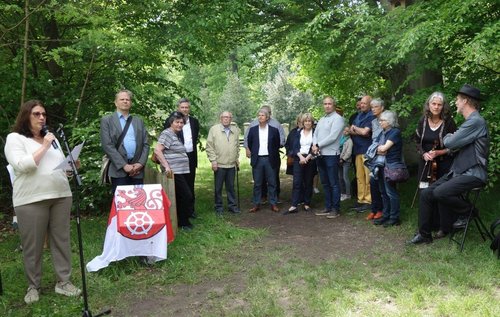 Mehrere Personen hören einer Frau zu, die am Mikrofon spricht
