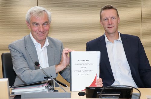 Zwei Männer halten Haushaltsplan in den Händen