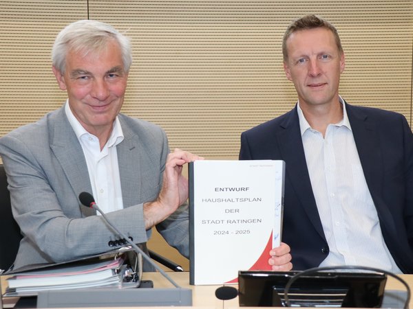 Zwei Männer halten Haushaltsplan in den Händen