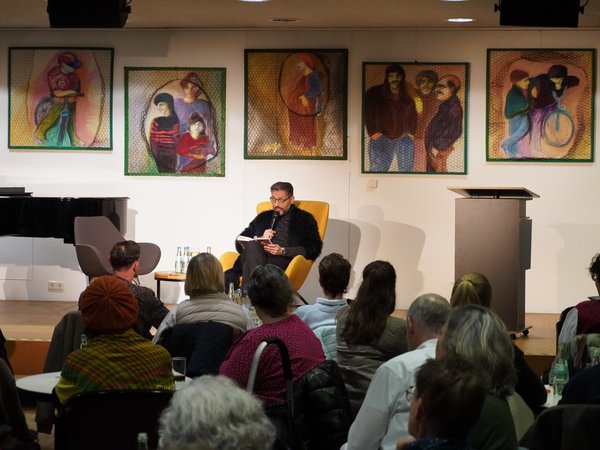 Mann auf Bühne liest vor Zuschauern