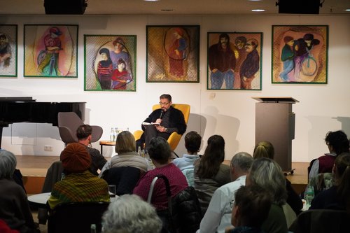 Mann auf Bühne liest vor Zuschauern