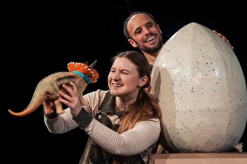 Ein Mann und eine Frau mit einem riesigen Ei und einem kleinen Dino