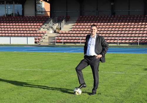 Mann steht mit Fuß auf dem Ball auf dem Rasen im Stadion