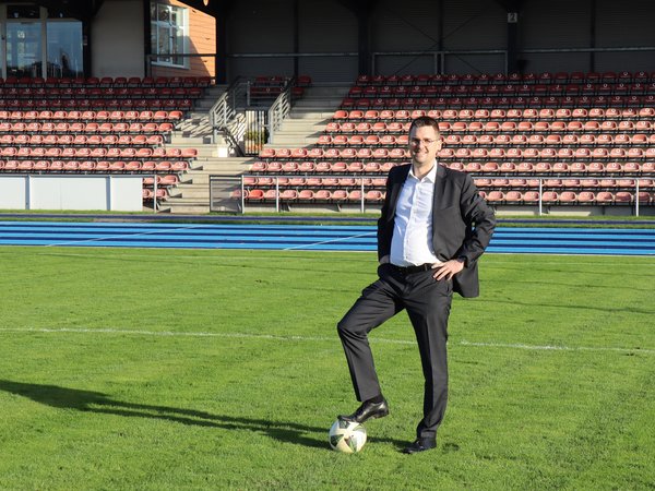Mann steht mit Fuß auf dem Ball auf dem Rasen im Stadion