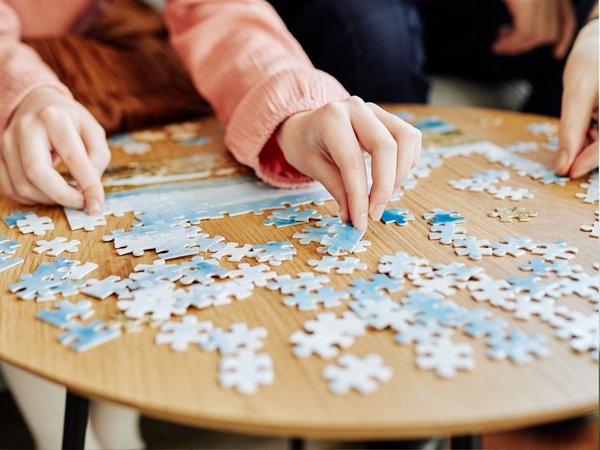 Mehrere Personen puzzeln gemeinsam an einem Tisch.