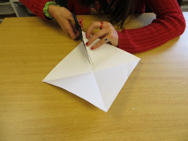 Hand schneidet mit einer Schere Papier