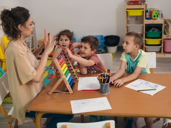 Spielszene in einer Kita mit einer Frau und drei Kindern