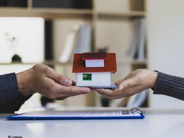 Zwei Hände halten ein Miniaturhaus 