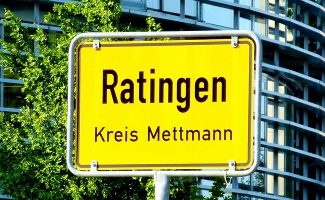 Ortseingangsschild der Stadt Ratingen vor einem modernen Bürogebäude