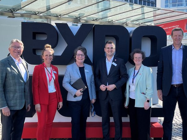 Mehrere Personen vor dem Schriftzug EXPO
