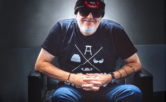 Markus Krebs sitzt auf einem Stuhl und lächelt.