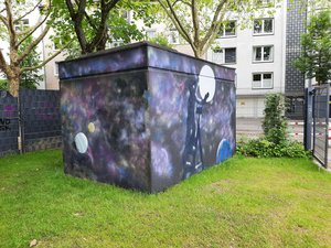 Traffohaus auf einem Spielplatz, das mit Weltallmotiven besprayt wurde
