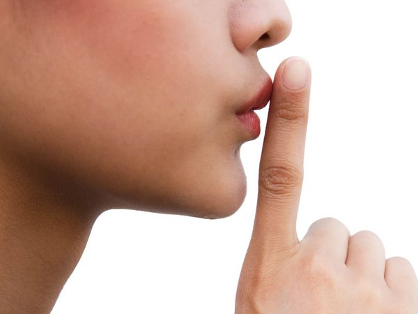 Frau hält einen Zeigefinger vor den Mund