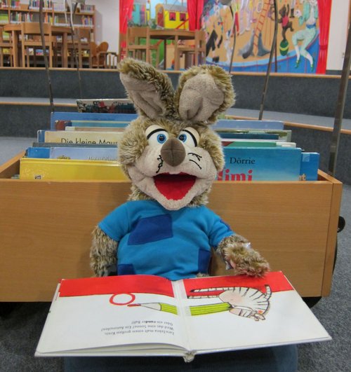 Plüschtier sitzt vor einem Buch. 