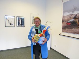 Eine Frau hält eine bunte Kunstfigur in die Kamera.