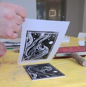 Ein Linolschnitt mit Wellenmotiv wird auf Papier gedruckt