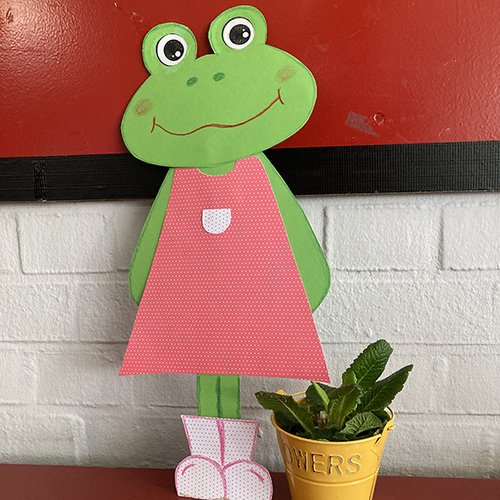 Frosch als Pappfigur neben einem Blumentopf