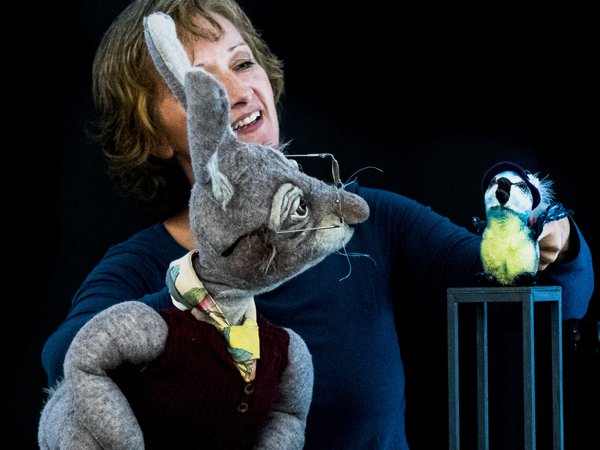 Puppenspielerin mit einer grauen Hasen-Puppe und einem Vogel 