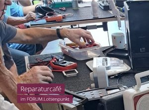 Man sieht Personen unterschiedliche elektronische Kleingeräte reparieren, sowie den Schriftzug "Reparaturcafé im Forum.Lotsenpunkt"