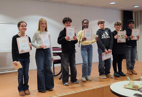 Sieben Kinder/Jugendliche stehen mit Urkunden auf einer Bühne