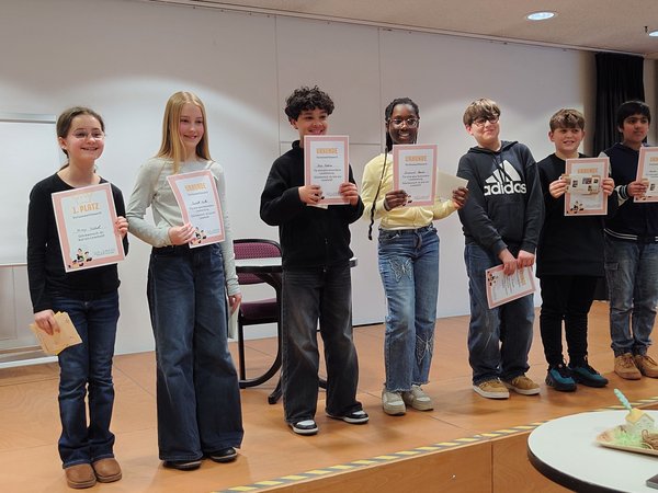 Sieben Kinder/Jugendliche stehen mit Urkunden auf einer Bühne