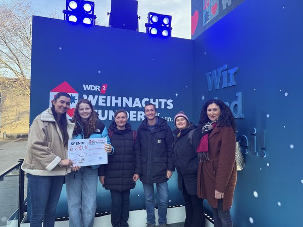 Mehrere Personen mit einem Spendenscheck