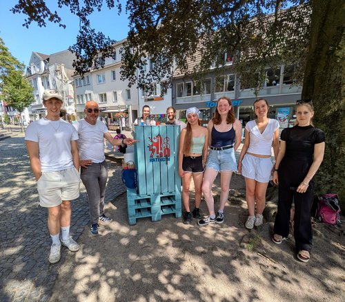 Mehrere Personen stehen rund um einen bemalten Strandkorb