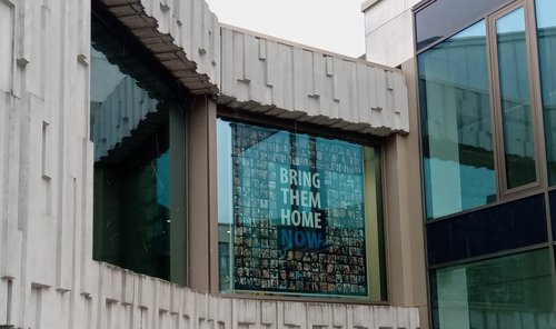 Banner mit dem Appell "Bring them home now" hängt in einem großen Fenster
