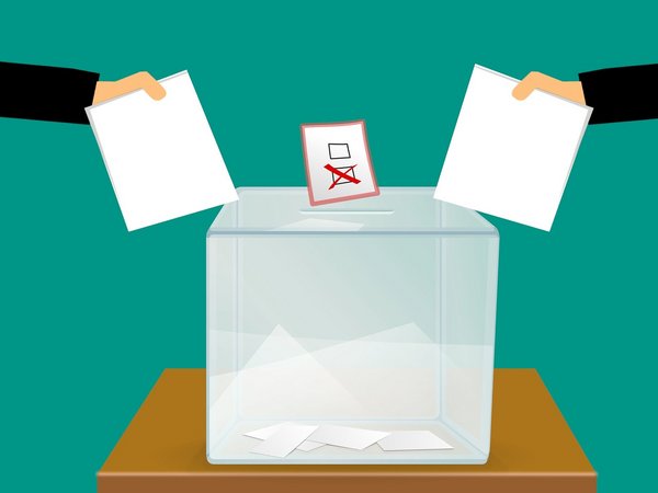 Grafik: Zwei Hände mit Zetteln, davor eine Wahlurne