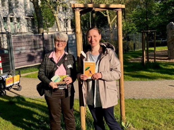 Zwei Frauen mit Broschüren vor einem Baum