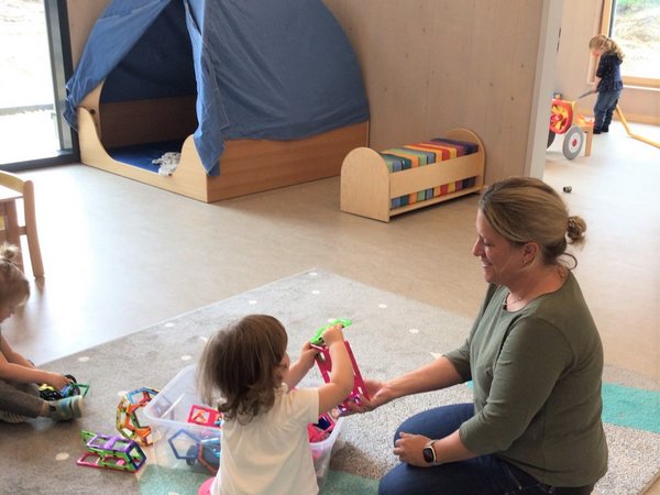 Eine Frau und ein Kind hocken spielend auf dem Boden 