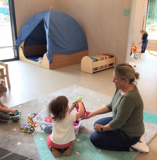 Eine Frau und ein Kind hocken spielend auf dem Boden 
