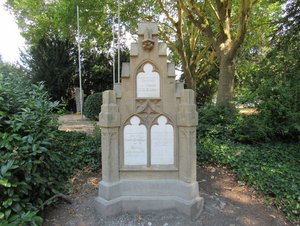 Großer Grabstein aus Sandstein, umgeben von Begrünung